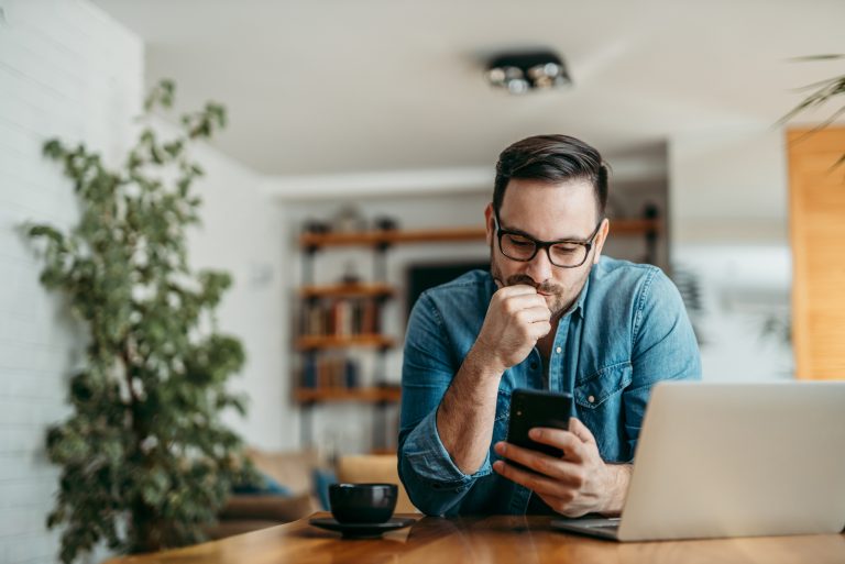 un homme imaginaire est assis à une table et les touches sur le téléphone