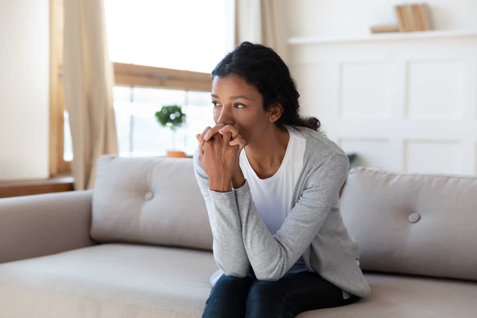 femme assise sur le canapé à la maison regarder à distance