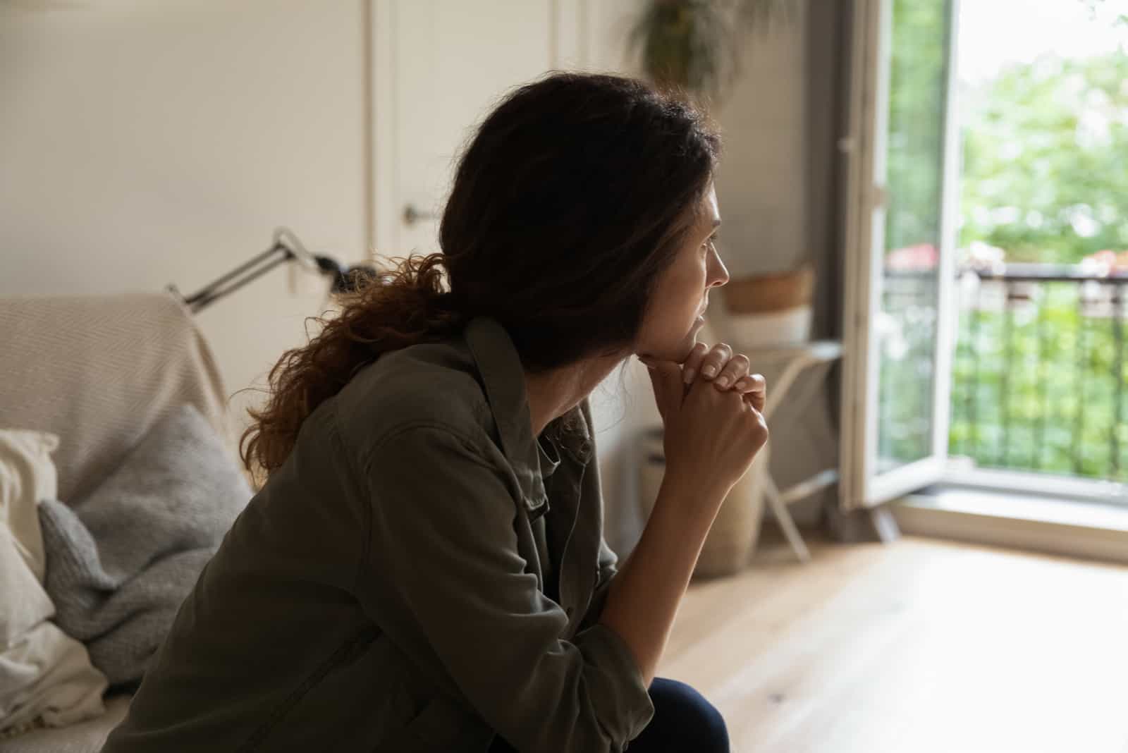 femme assise sur le canapé à la maison regarder à distance