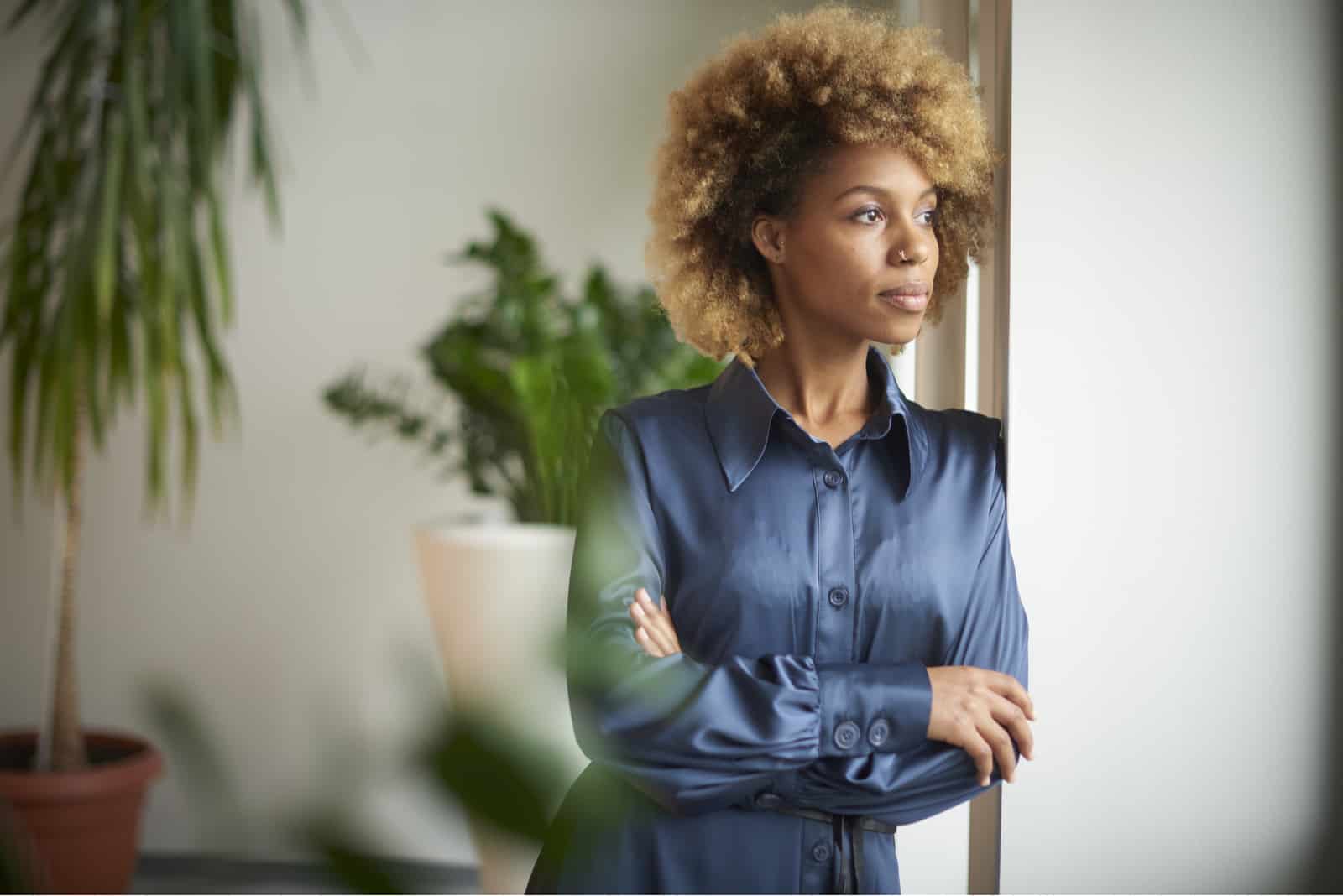 femme debout avec les bras croisés et regardant par la fenêtre