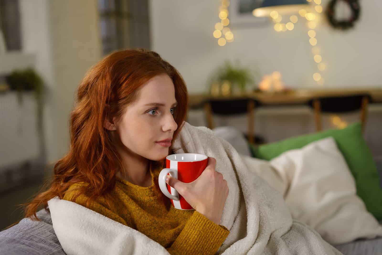 femme rousse assise sur un canapé à la maison