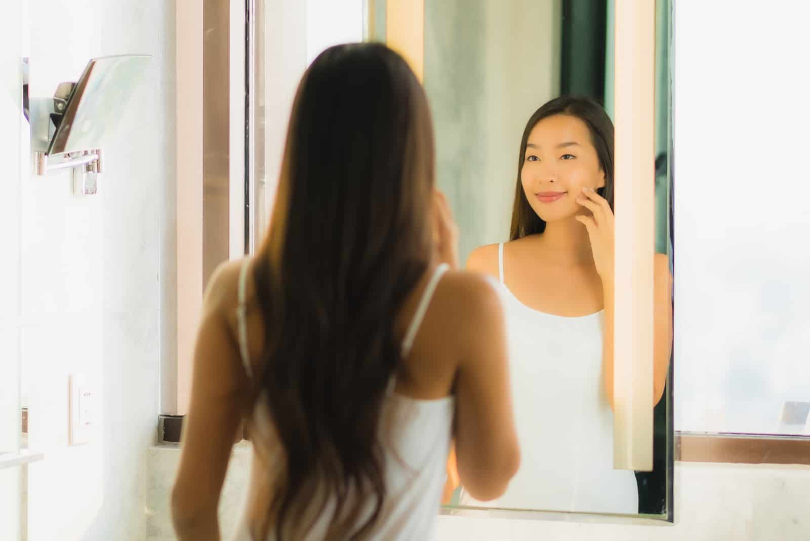 femme vérifier son visage et le visage dans l'intérieur de la salle de bain