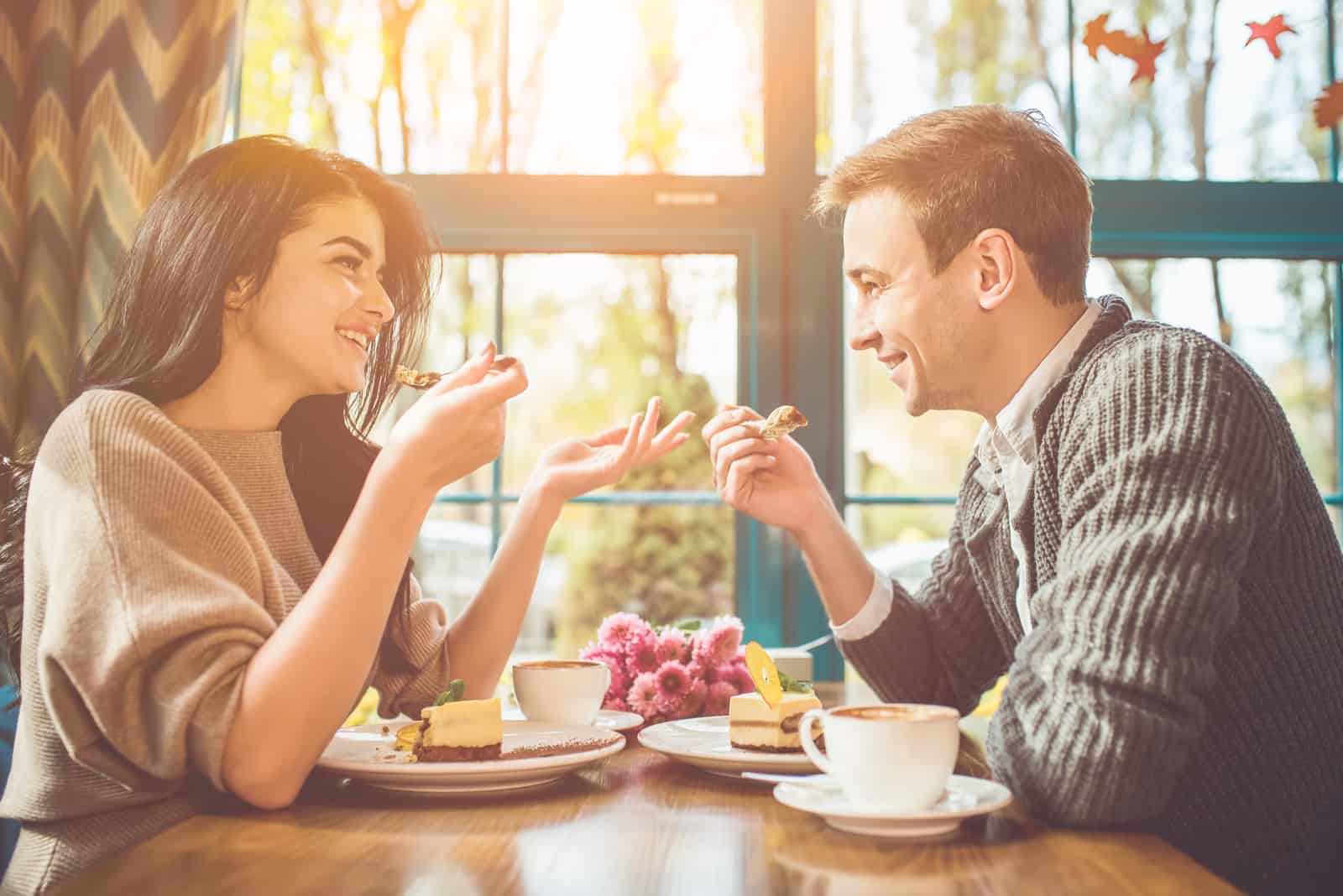 heureux homme femme manger a gâteau dans les café