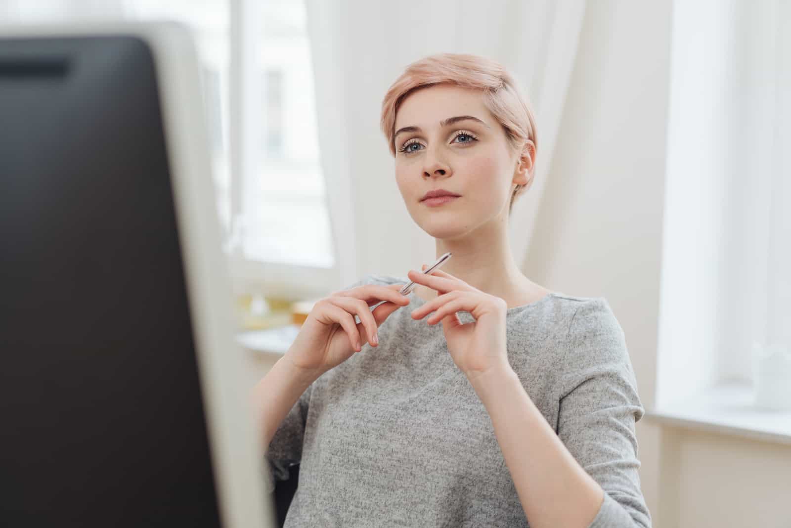 jeune femme assise à un grand écran de bureau
