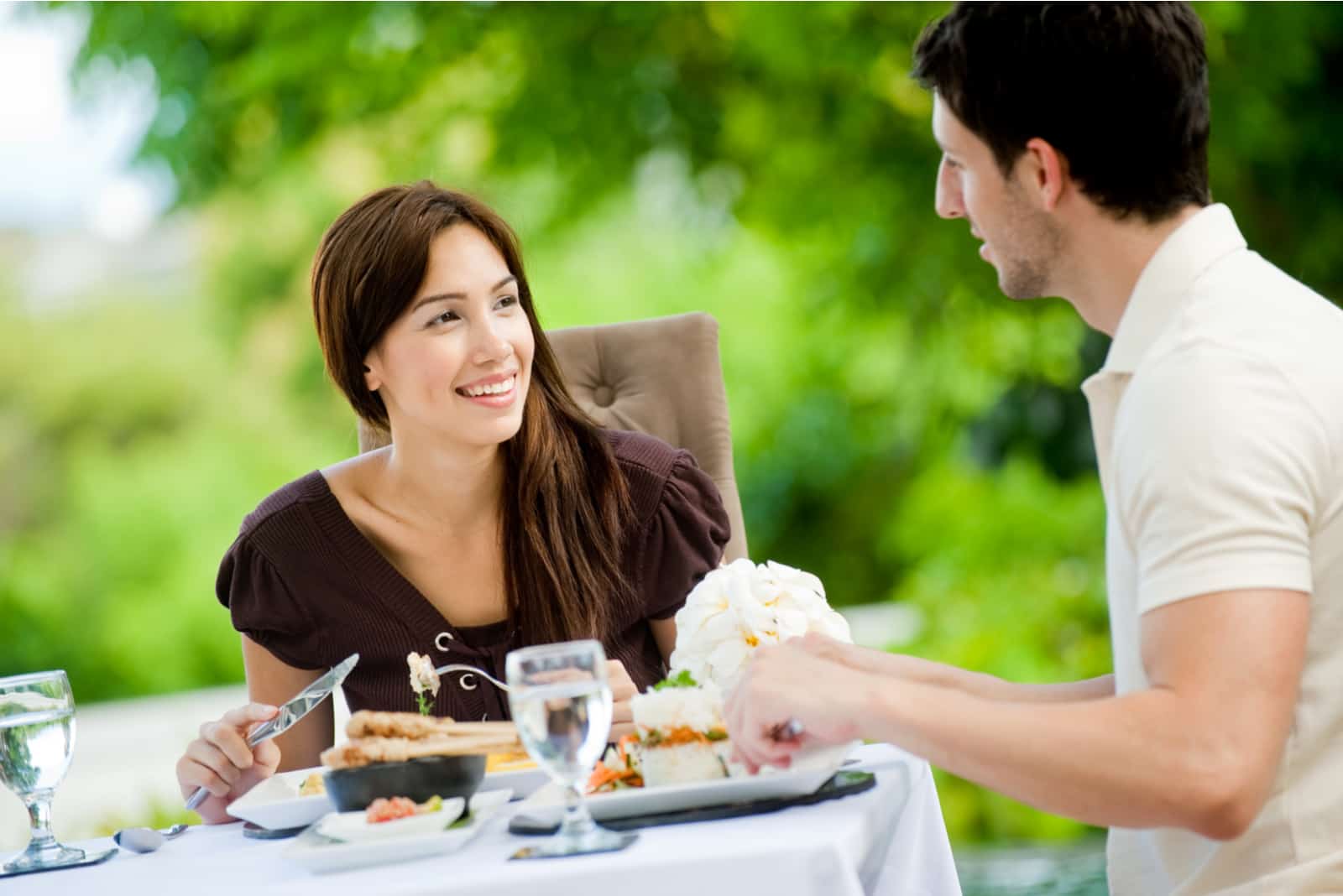 un couple souriant assis à une table en train de déjeuner et de parler