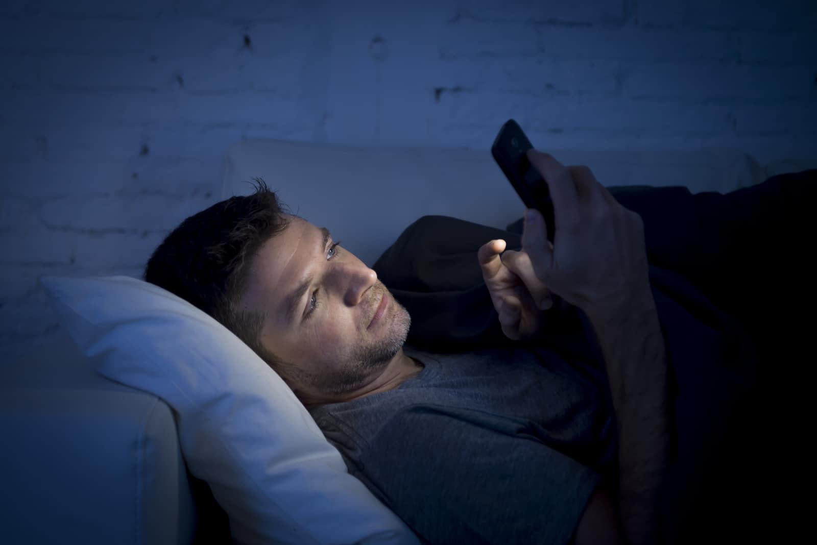 un homme est allongé dans son lit et les touches du téléphone