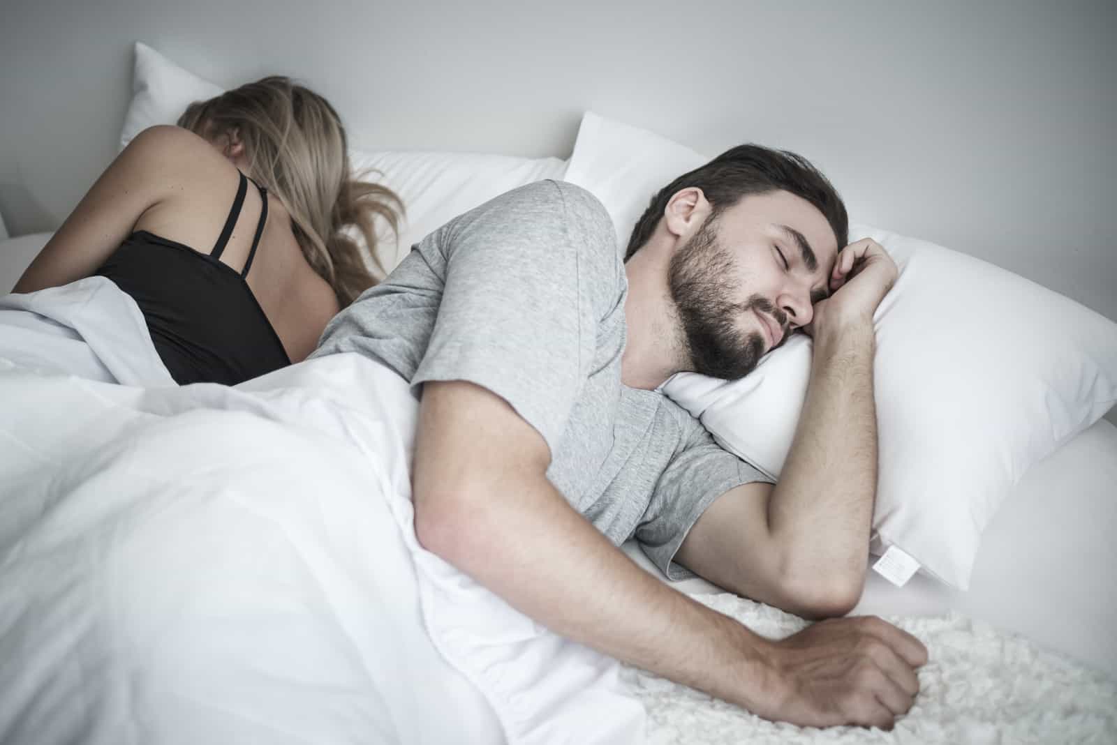 un homme et une femme dorment dans leur lit