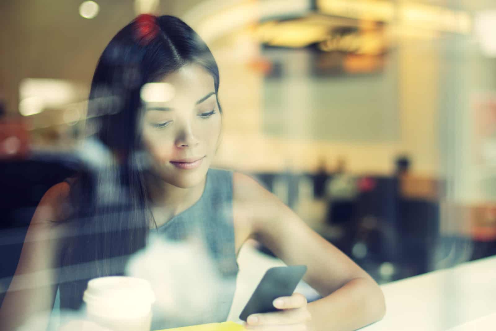 une femme assise dans un café et en appuyant sur un téléphone 
