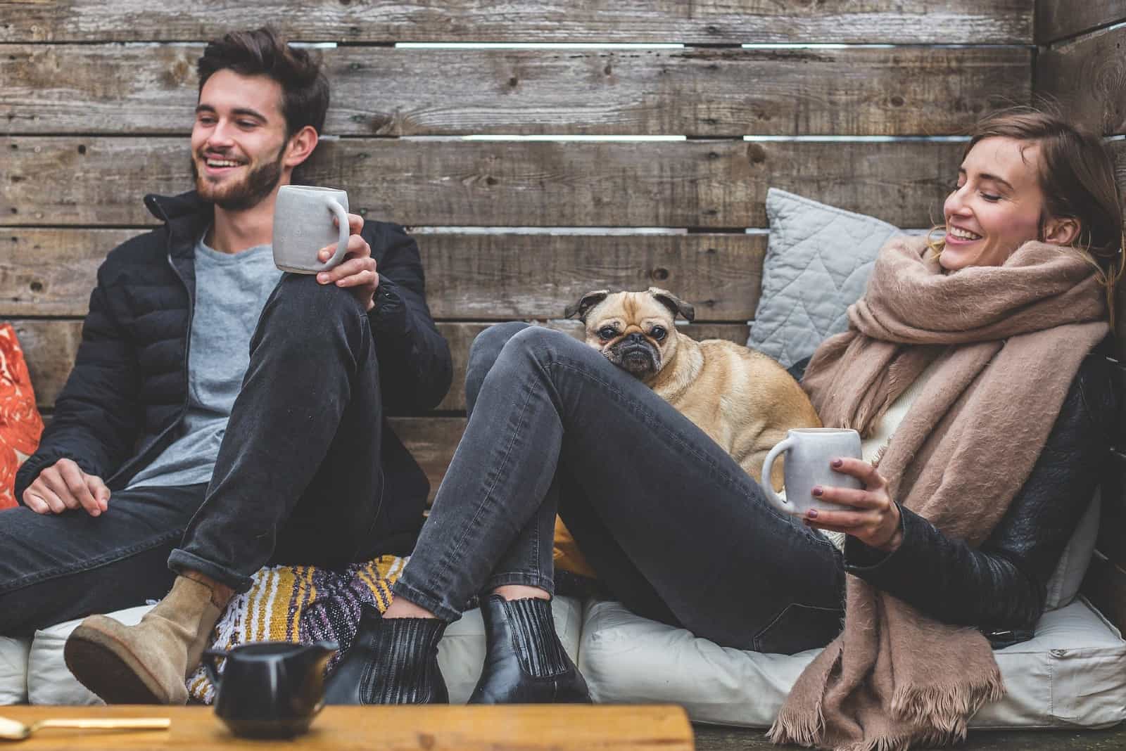 homme et femme souriant assis près du mur en bois