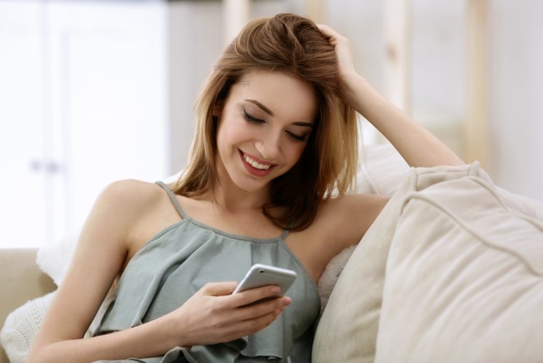 une femme souriante est assise et les touches sur le téléphone