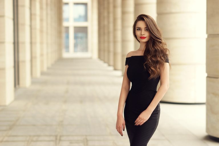 une belle femme aux longs cheveux noirs dans une robe noire se dresse