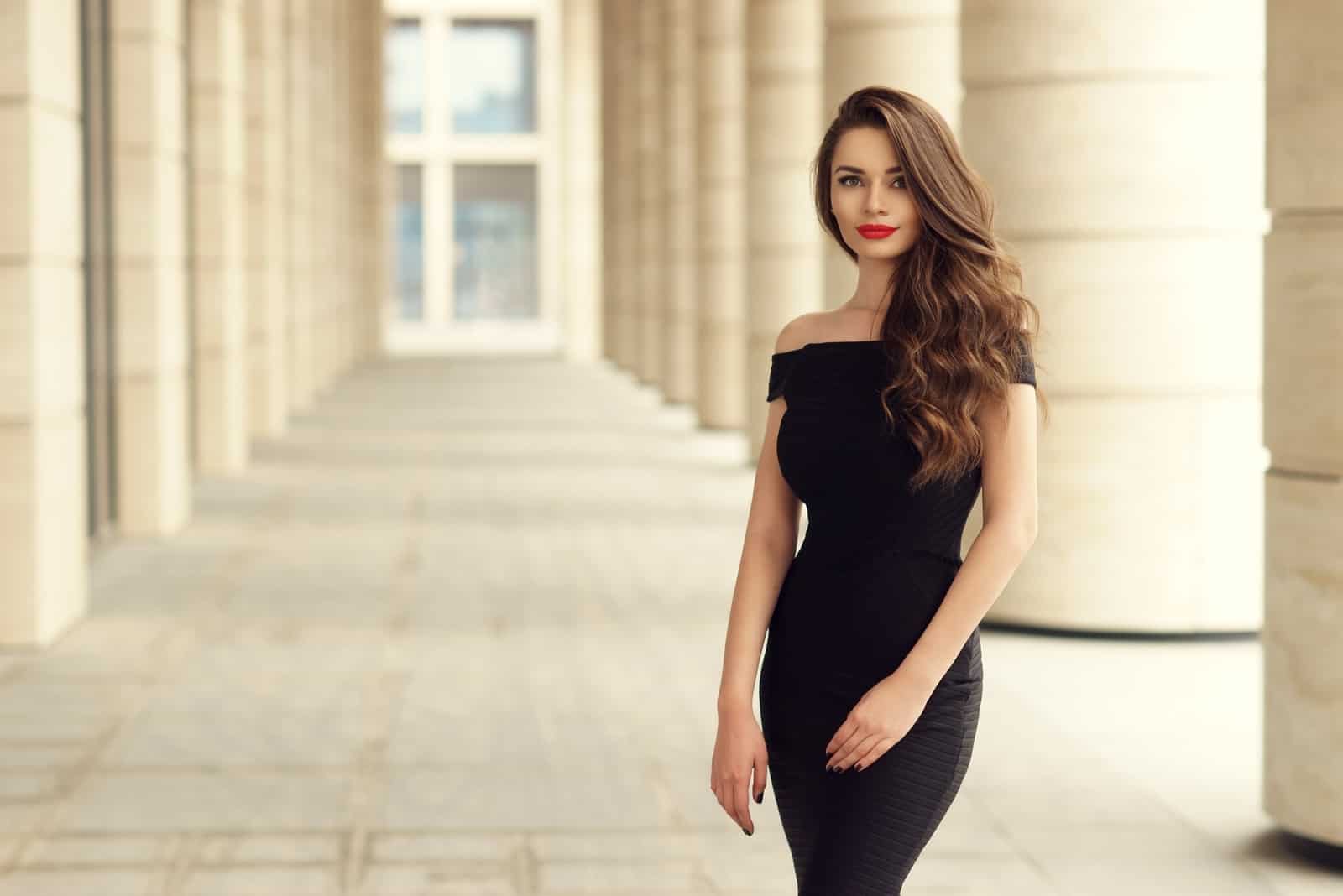 une belle femme aux longs cheveux noirs dans une robe noire se dresse
