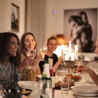 femmes portant un toast avec des verres à vin tout en étant assises à une table