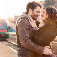 un couple d'amoureux dans une gare s'embrassant et se serrant dans les bras