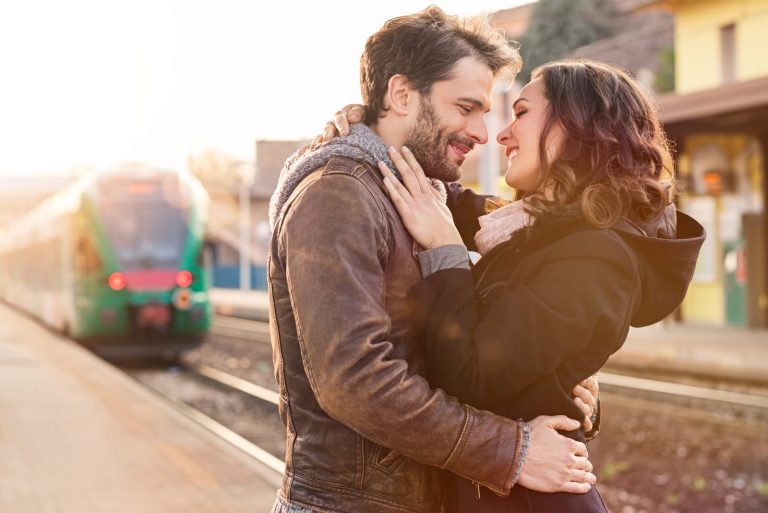 un couple d'amoureux dans une gare s'embrassant et se serrant dans les bras