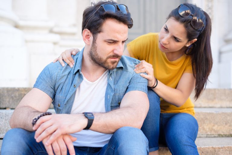 femme s'excusant auprès de l'homme assis dans les escaliers