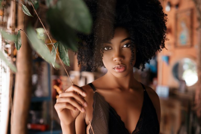 femme aux cheveux bouclés debout près de la plante