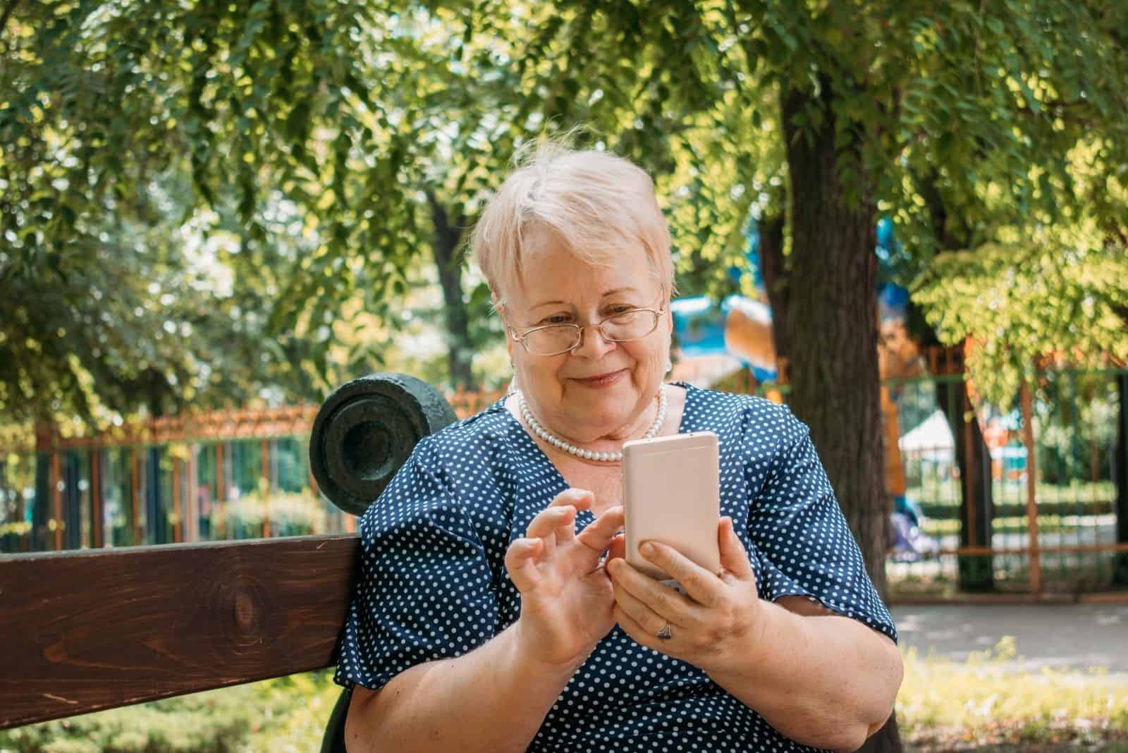 Joyeuse vieille femme avec smartphone au parc