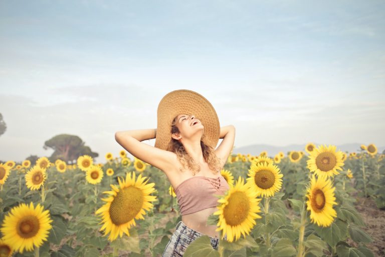 femme heureuse, à, chapeau, debout, dans, champ tournesols