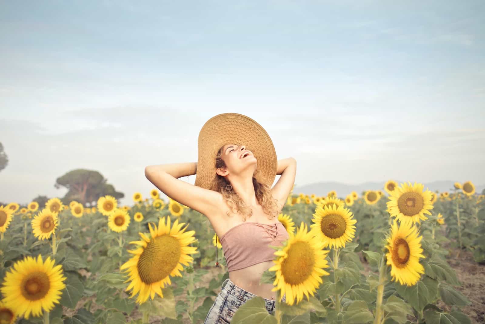 femme heureuse, à, chapeau, debout, dans, champ tournesols
