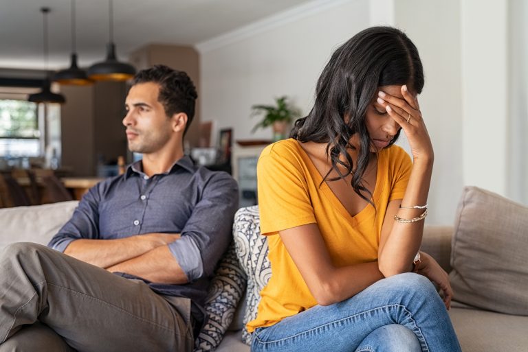 Femme triste en t-shirt jaune assis près de l'homme sur le canapé