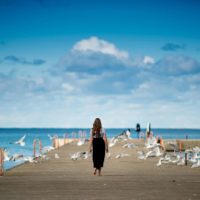 femme debout sur un quai entouré d'oiseaux