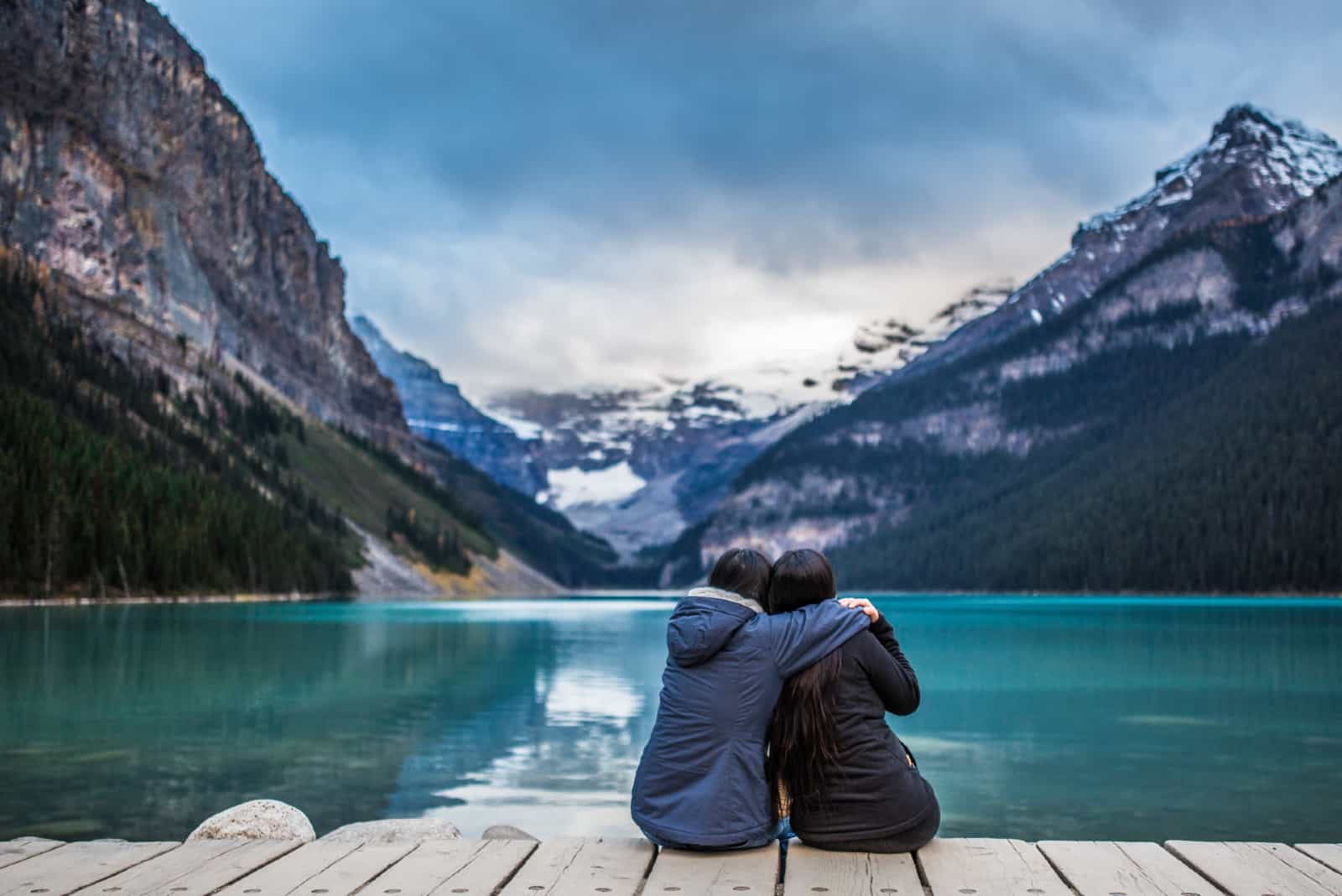 Deux amies serrant assis près du lac