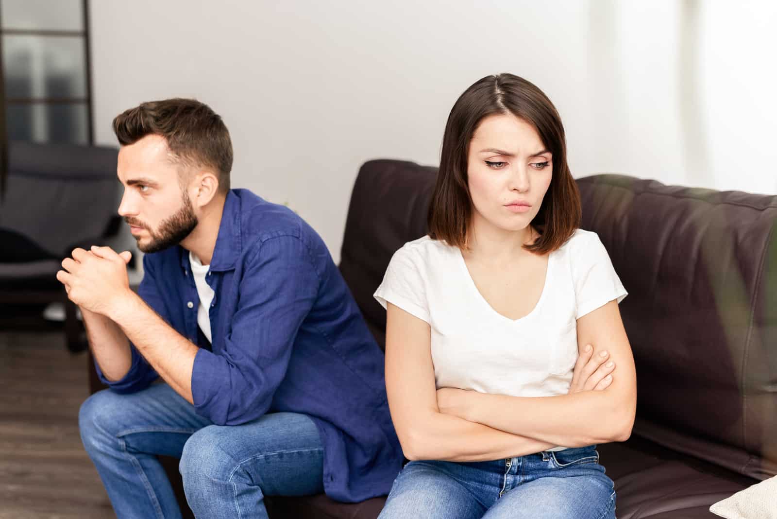 Homme en colère et femme en t-shirt blanc assis sur un canapé