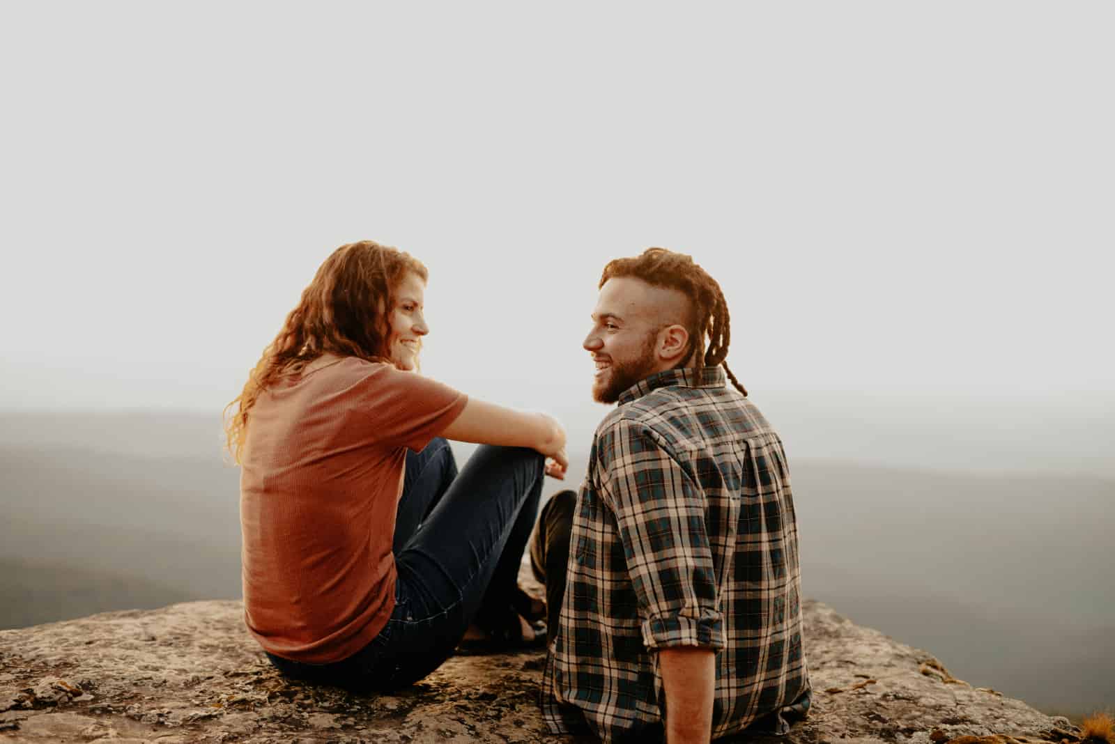 homme et femme souriant assis sur un rocher