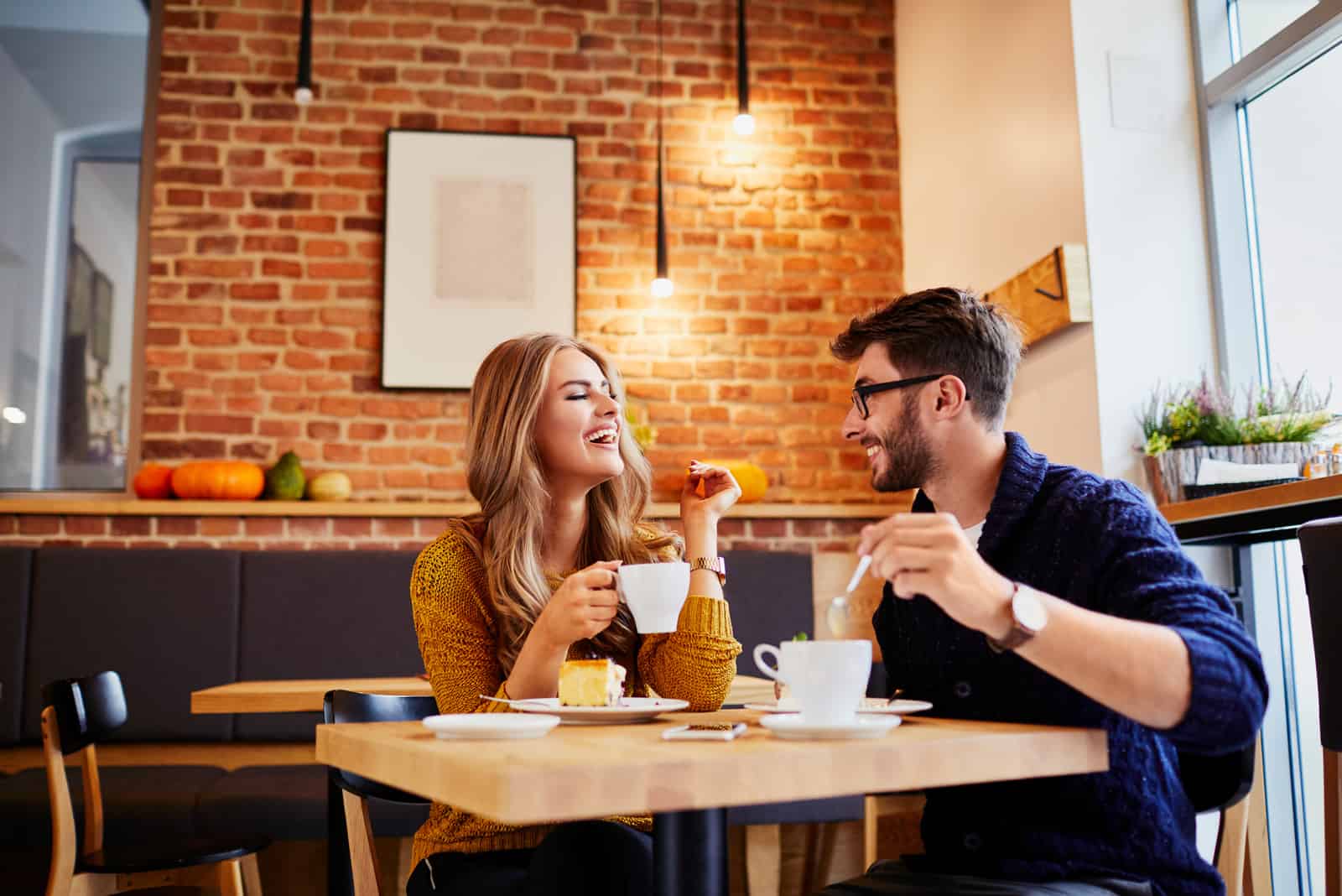 homme et femme riant alors qu'il était assis dans le café