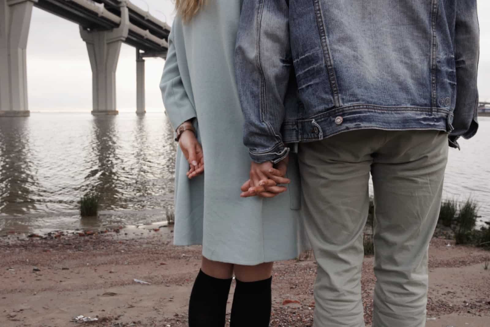 homme et femme tenant par la main en se tenant debout près de la rivière