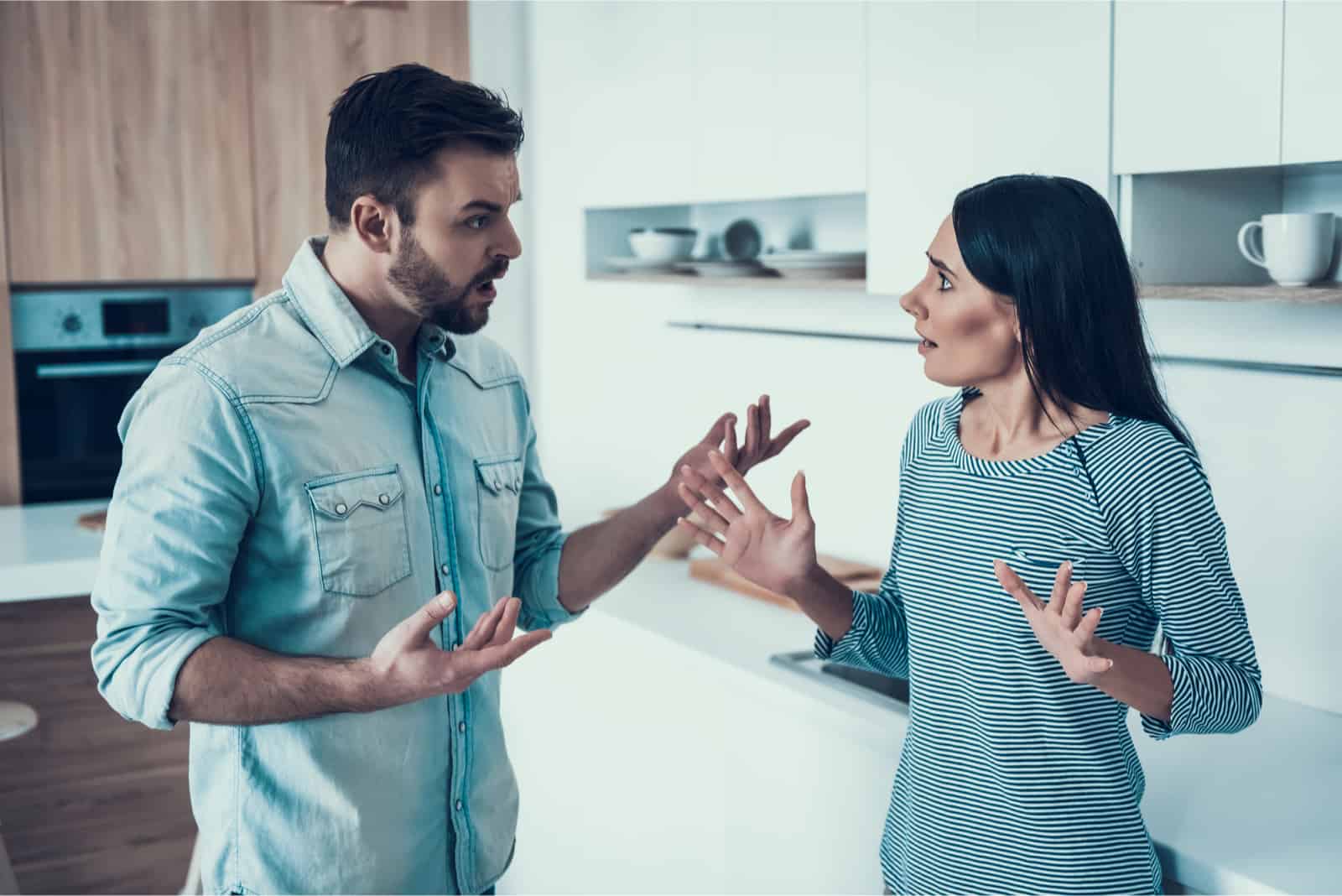 homme et femme se disputant en position debout dans la cuisine