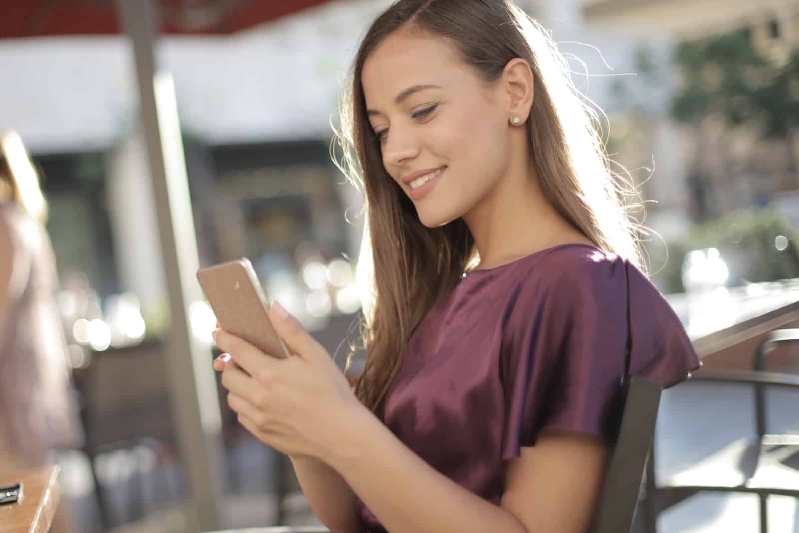 femme heureuse séance extérieur regarder smartphone