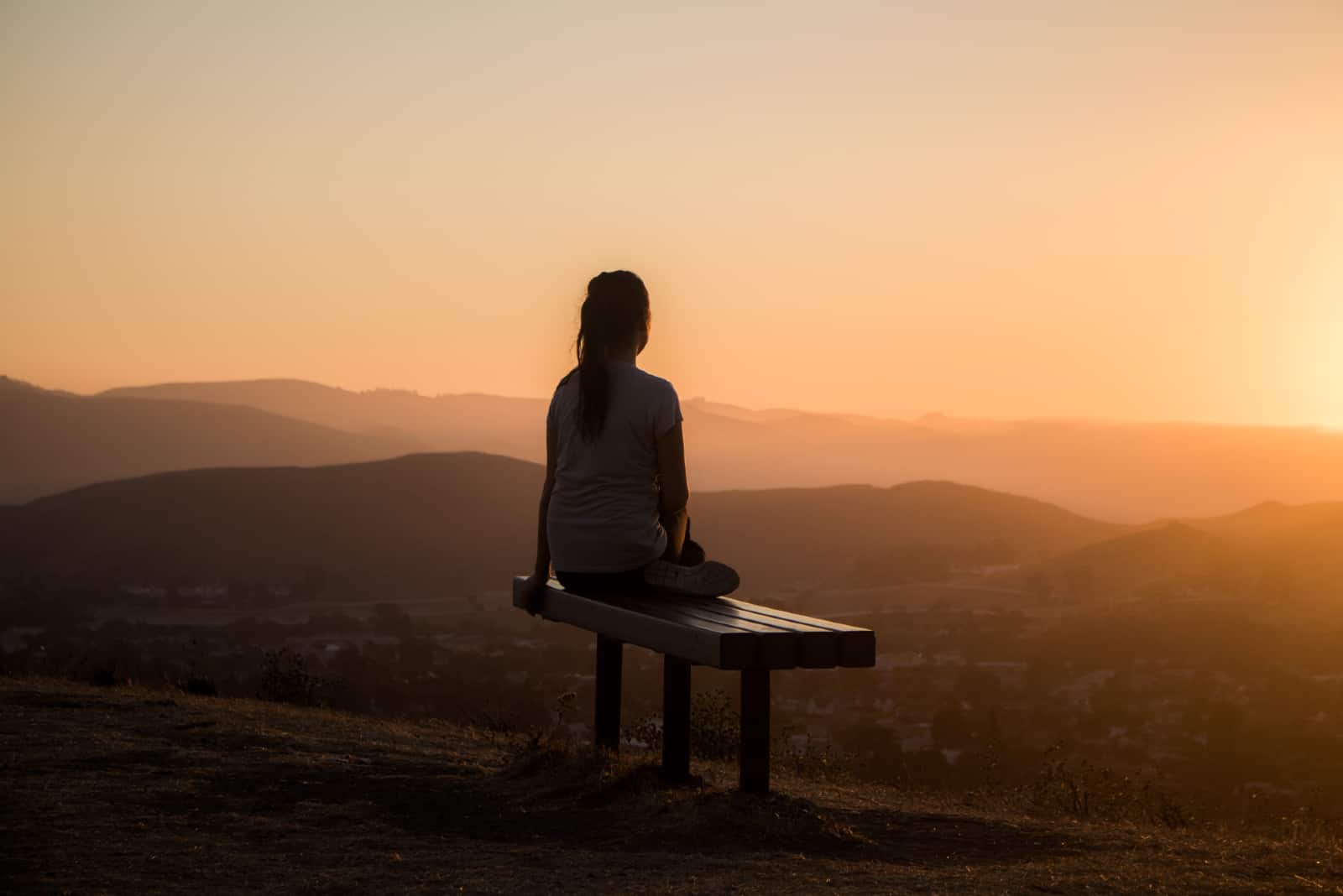 femme assise sur un banc en regardant la montagne