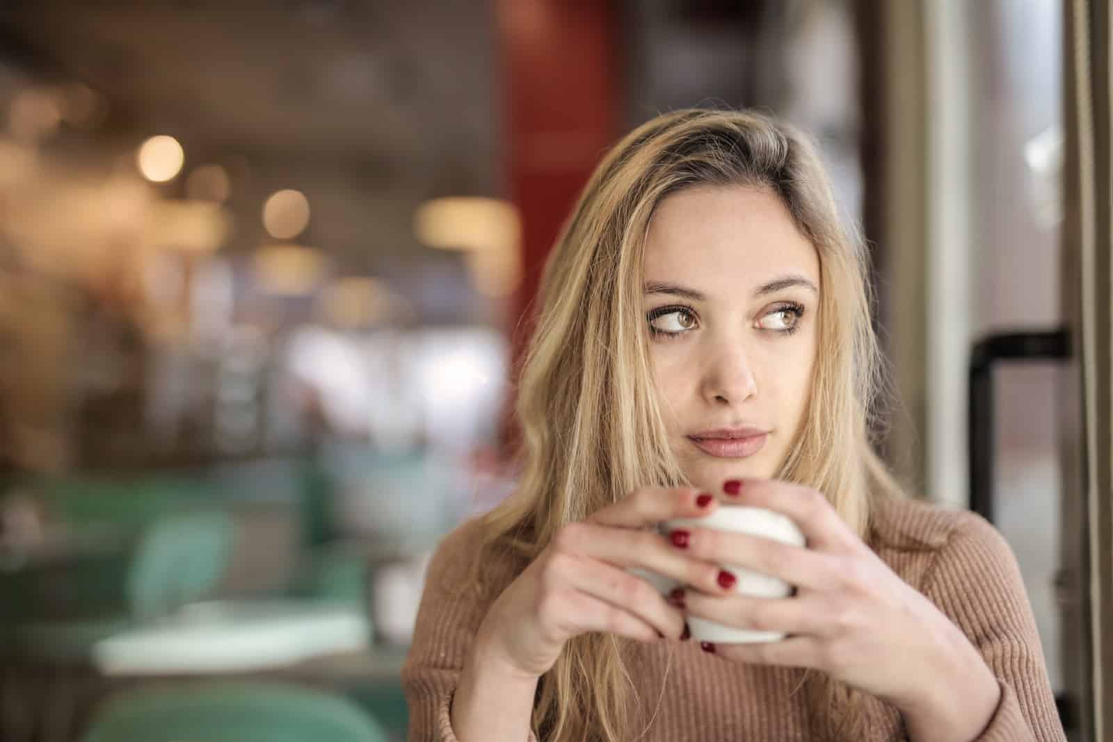 Femme buvant du café, assise dans un café