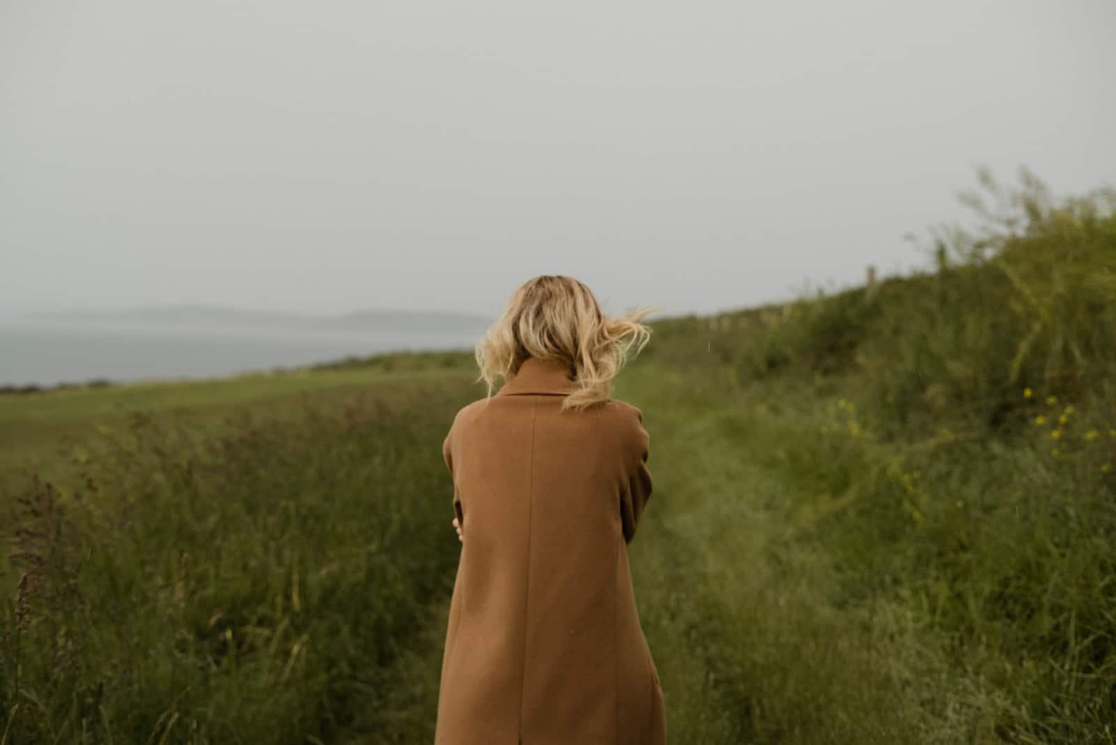 femme blonde en manteau brun debout sur terrain