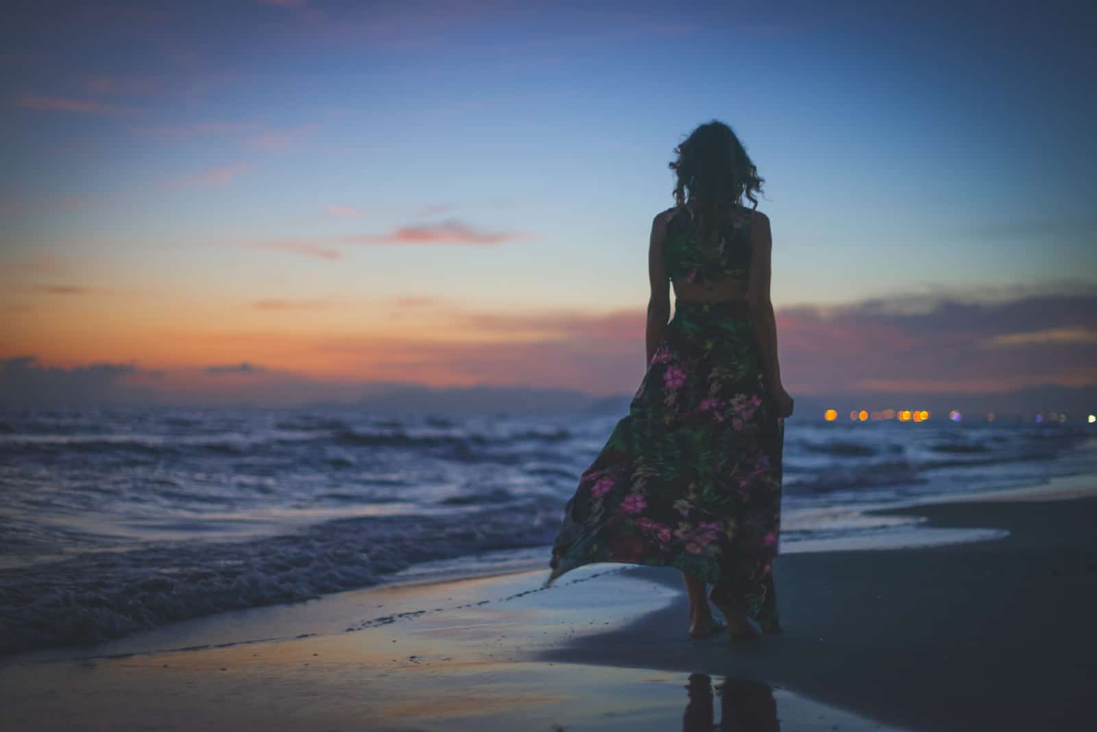 femme, dans, robe fleurie, debout, sur, plage, pendant, coucher soleil