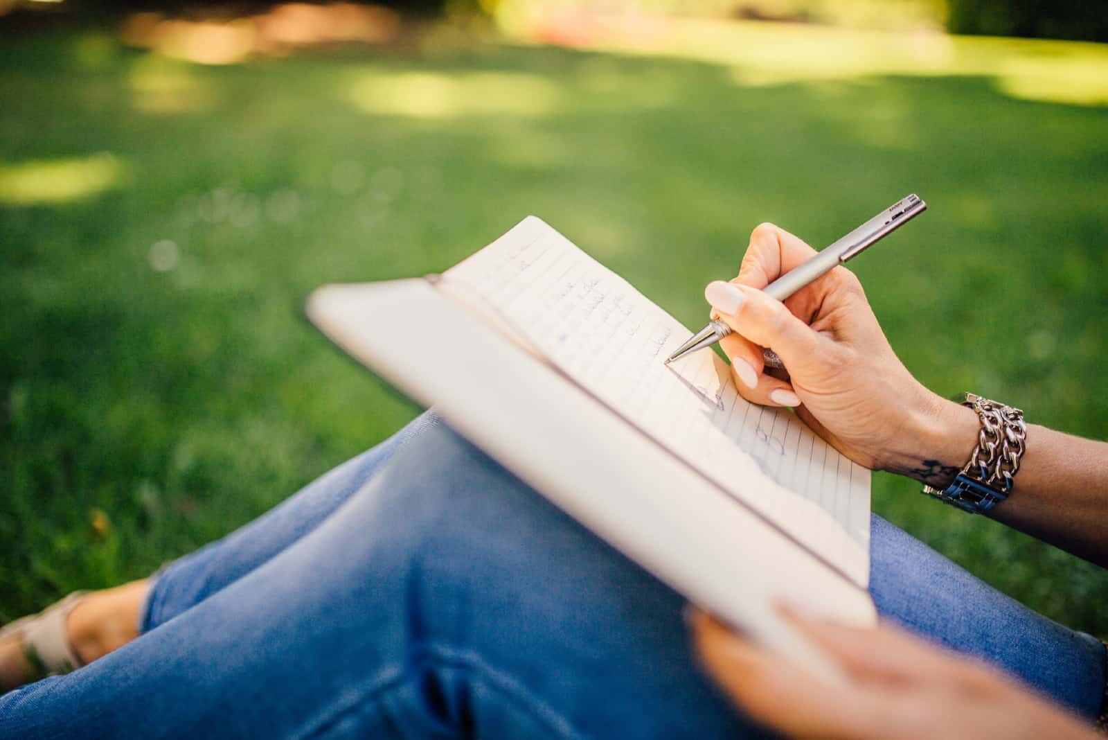 femme écriture sur cahier quoique séance herbe