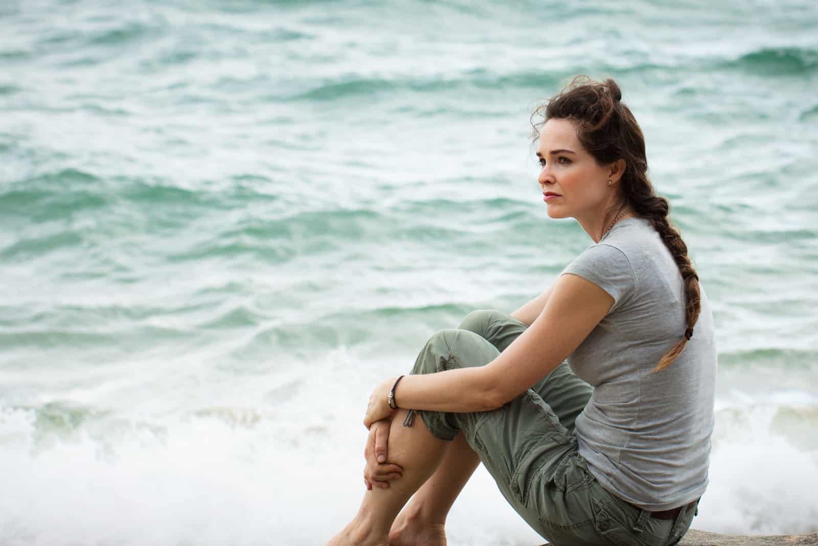 femme pensive assise au bord de l'océan