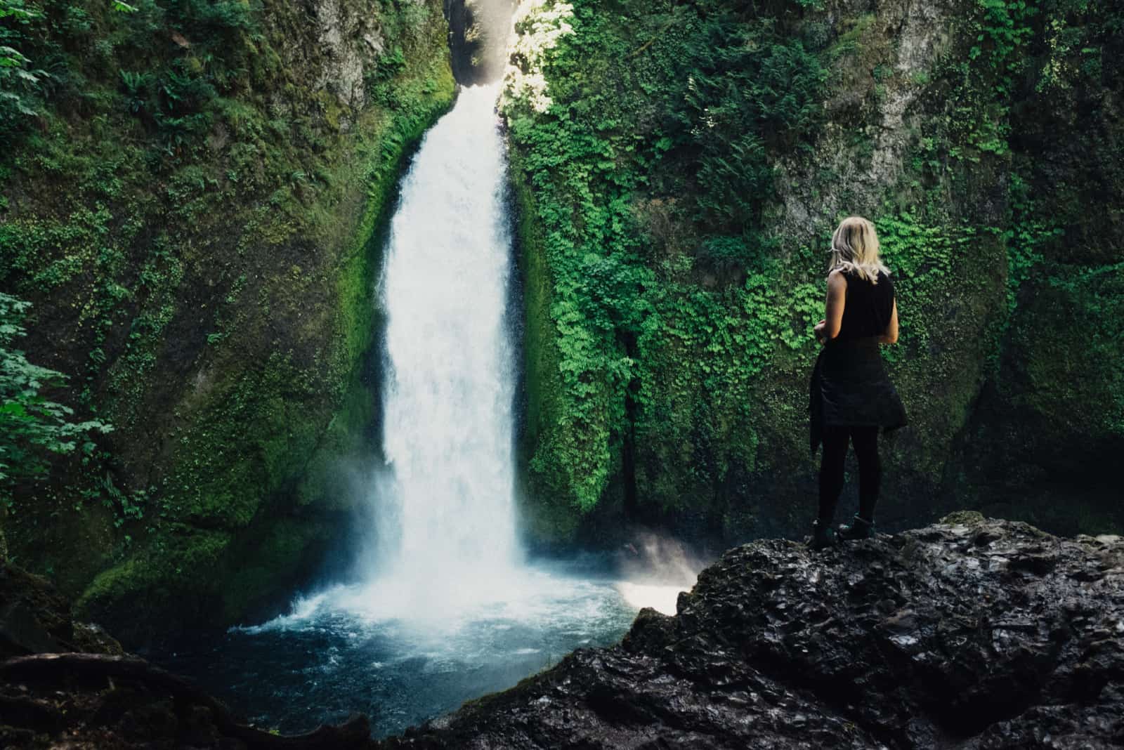 femme debout sur un rocher tout en regardant cascade