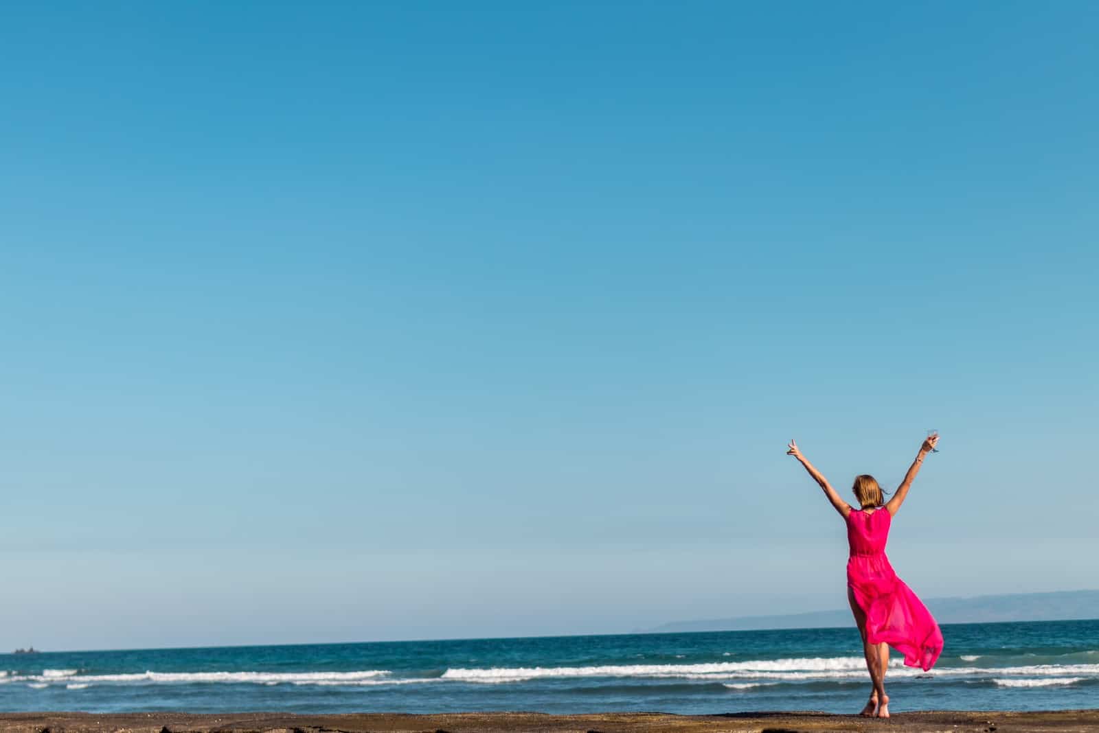 femme en robe rose regardant la mer