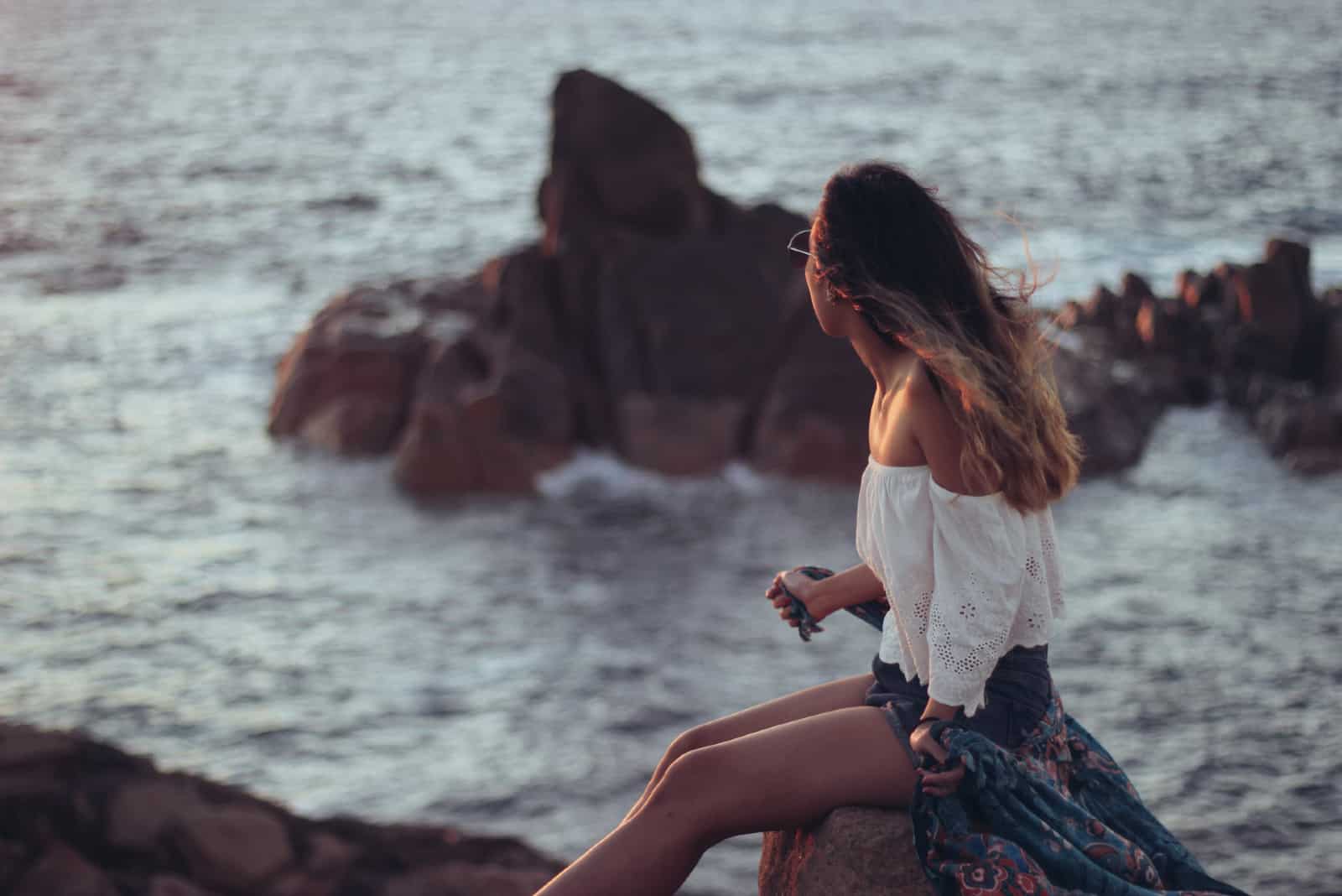 femme regardant la mer alors qu'il était assis sur un rocher