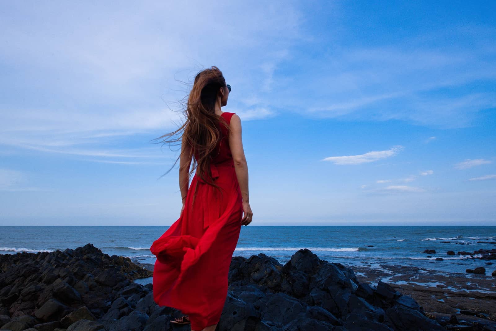 femme en robe rouge regardant la mer
