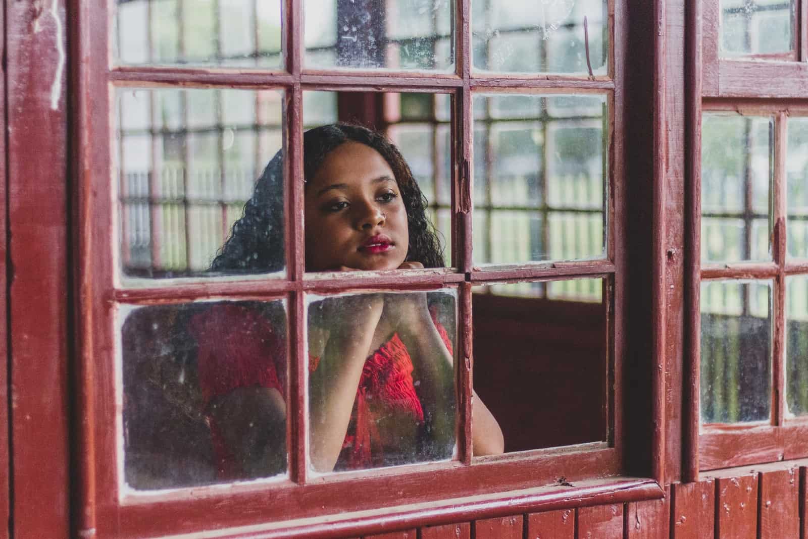 Femme pensive avec rouge à lèvres à la recherche d'une fenêtre