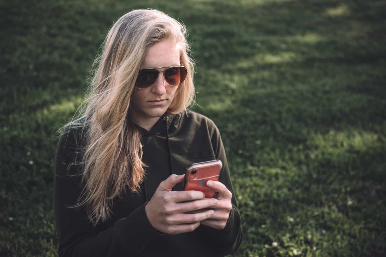 femme regardant smartphone assis sur l'herbe