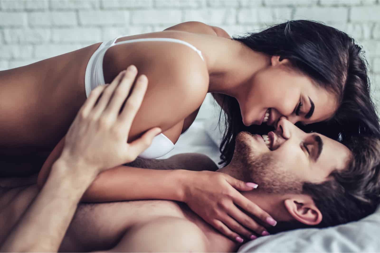femme sur le point d'embrasser l'homme en position couchée sur le lit