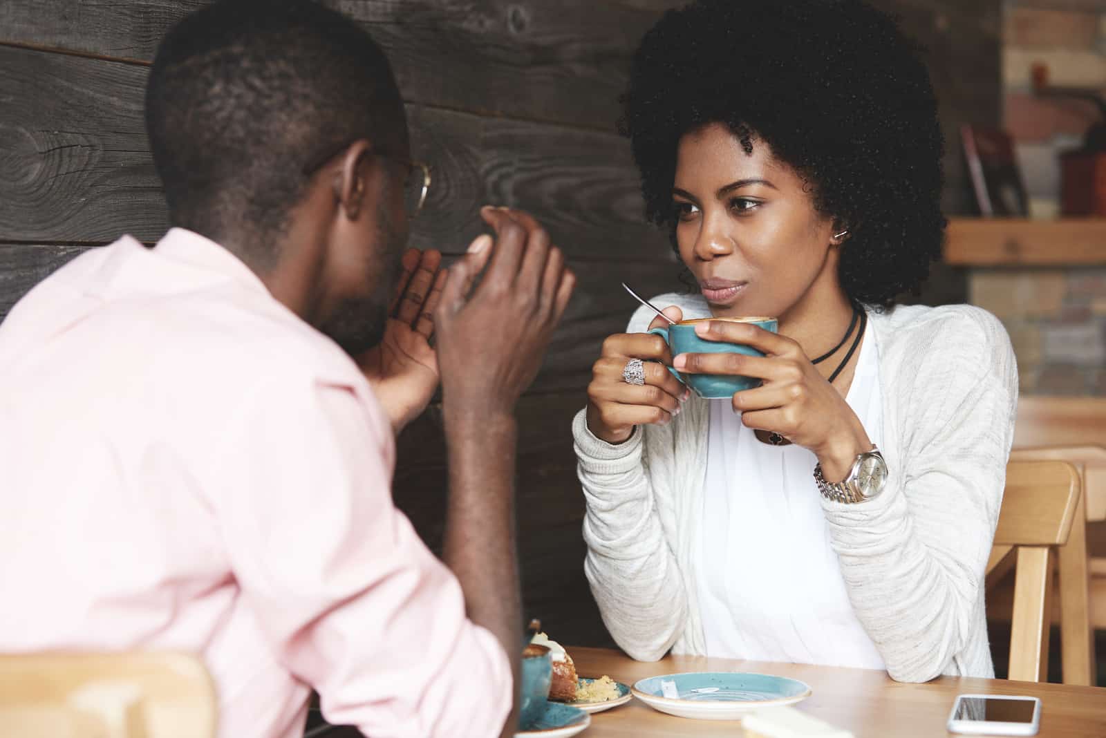 femme tenant une tasse de café, écoutant et regardant son petit ami