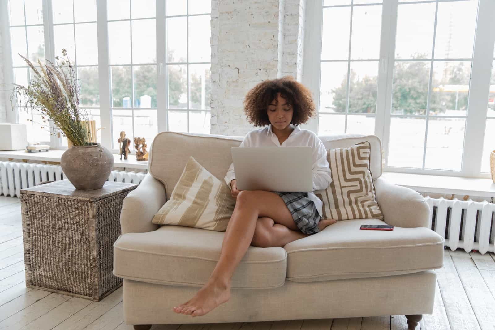 femme utilisant un ordinateur portable alors qu'il était assis sur un canapé