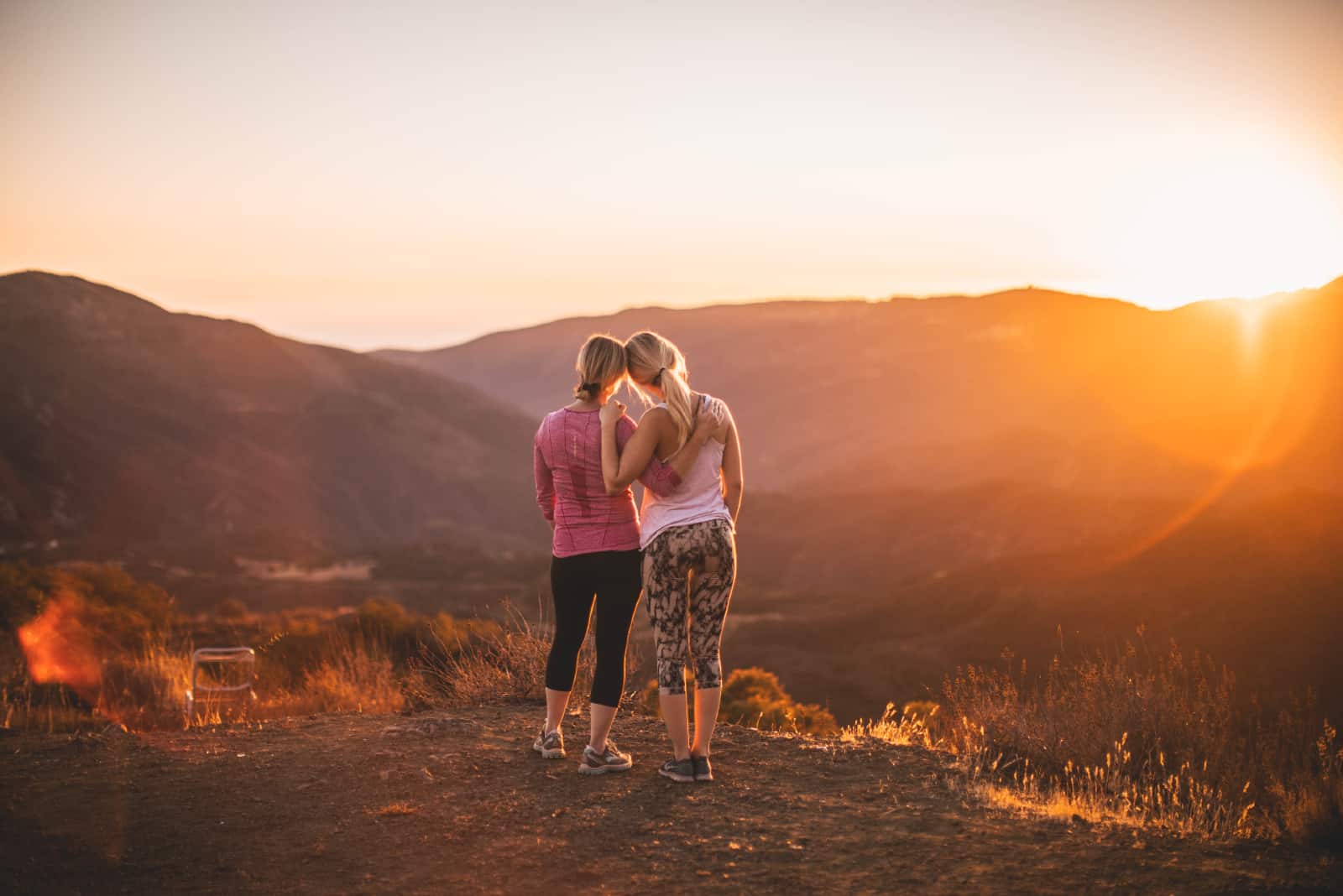deux femmes se serrant dans leurs bras debout au sommet de la colline