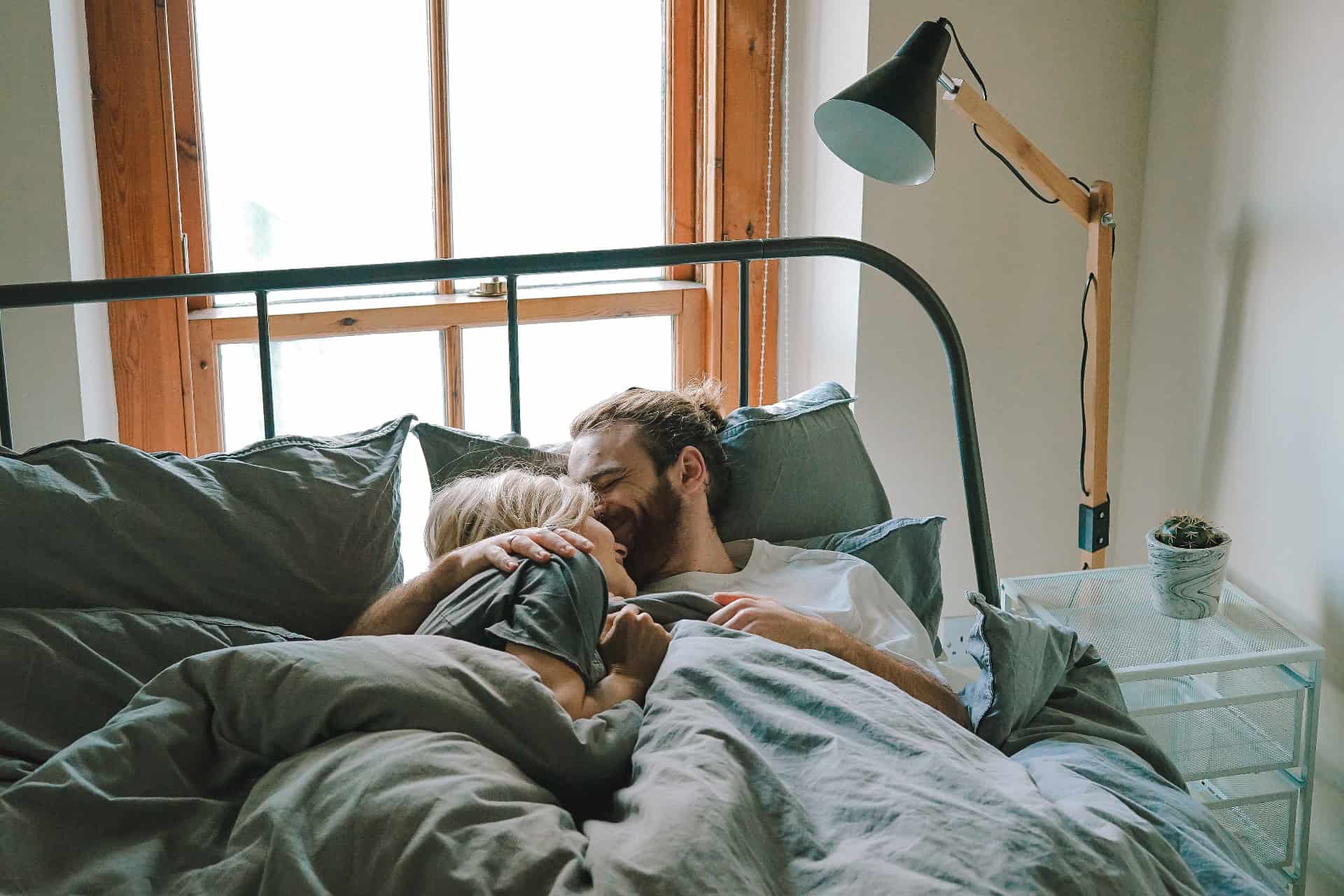 homme embrassant une femme allongée sur un lit